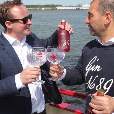 Founders of Gin 1689 standing together in Amsterdam with a bottle of their craft gin