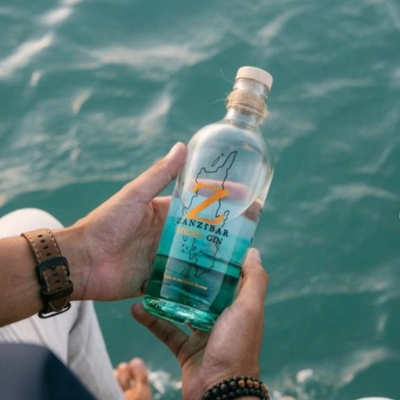 Zanzibar Gin bottle held above turquoise ocean waters — spiced craft gin from the Spice Island