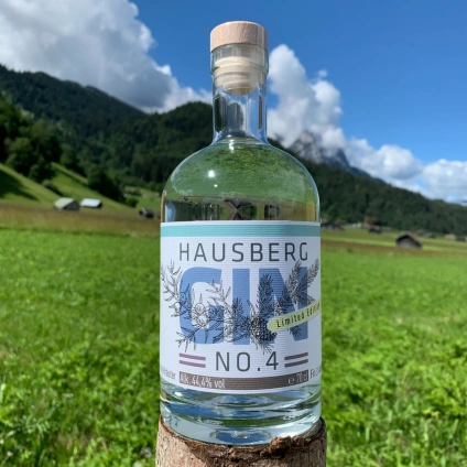 Hausberg Gin No. 4 bottle with alpine landscape and green meadow in background