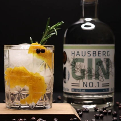 Hausberg No.4 Dry Gin with cocktail garnished with orange peel, rosemary and juniper