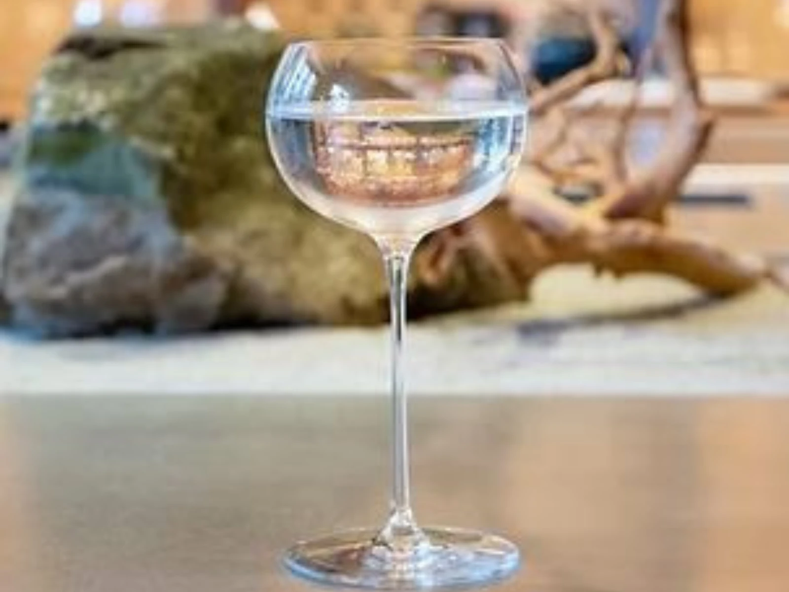 Elegant Nagasaki Martini with a clear cocktail on a bar counter, set against a softly lit background of bottles and Japanese-style décor.
