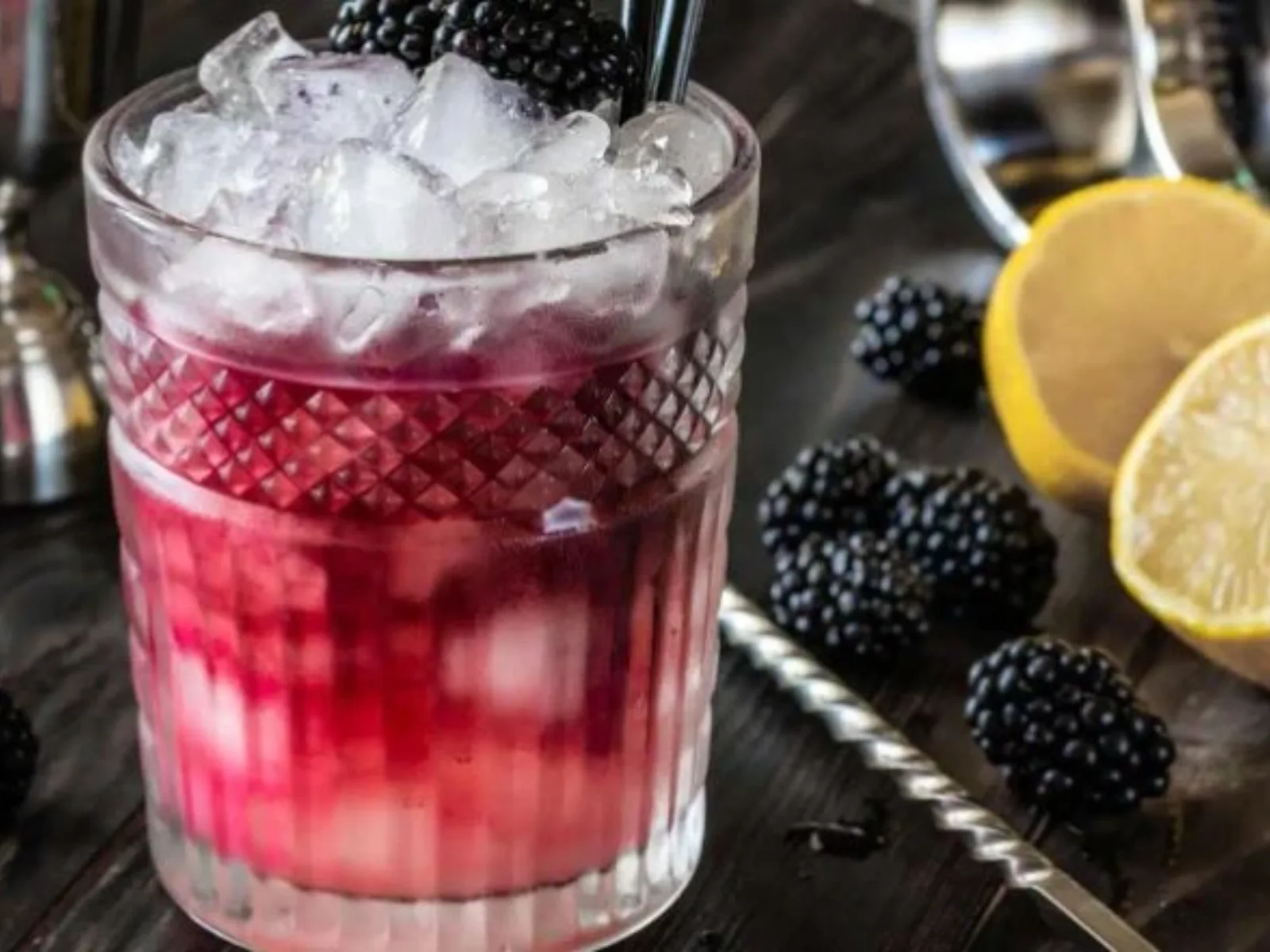 Snowdonia Bramble cocktail served in a cut-glass tumbler over crushed ice, garnished with blackberry and lemon, with layered berry tones.