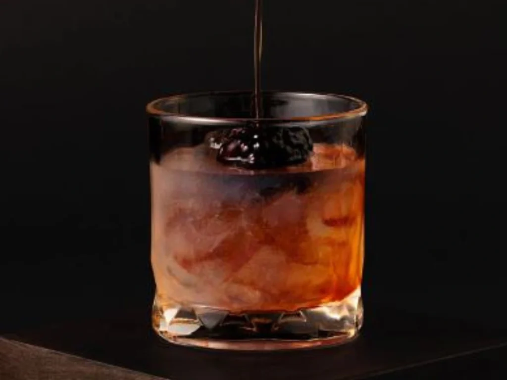 A vibrant Spiced Gin Bramble served in a rocks glass with crushed ice, blackberries, and a citrus twist, showcasing a bold and refreshing gin cocktail.