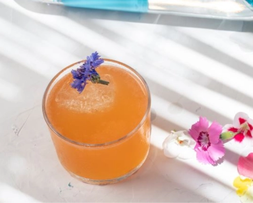 Stress Reliever served in a low glass with edible flower garnish