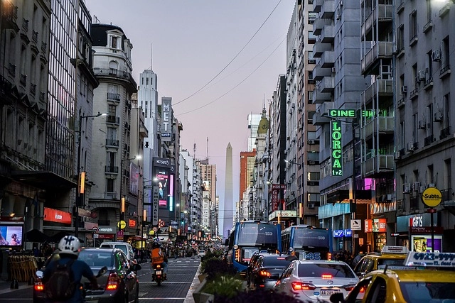 Busy street in Buenos Aires with traffic, buildings and the Obelisk in the distance