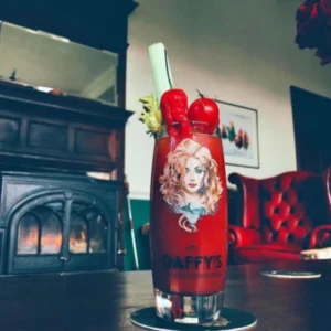Red Snapper cocktail with Daffy’s Gin, garnished with celery, tomatoes and peppers, served in a moody lounge with a Halloween vibe.