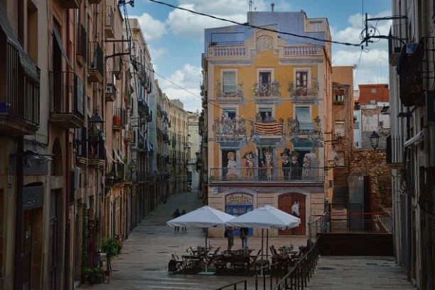 Spanish street with outdoor café and mural-painted building