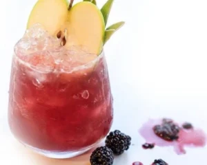 Apple Bramble cocktail served over crushed ice with apple slice and blackberries