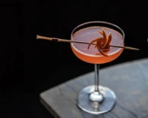 Jasmine gin cocktail served in a coupe glass with an orange flower garnish