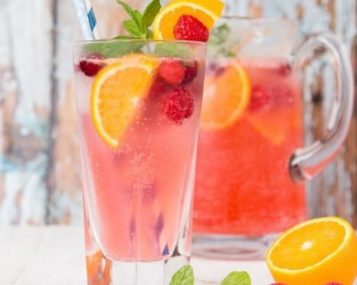 Raspberry gin spritz served over ice with orange slices and raspberries