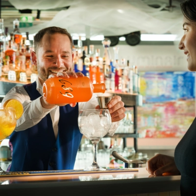 bartender pouring 1689 Dutch Orange Gin to prepare a fresh orange gin and tonic at the bar