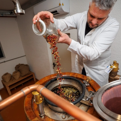 Distiller adding botanicals to a copper still during gin production